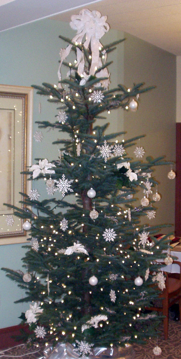 A 6 foot high Christmas tree covered with white and gold decorations including glass bulbs and snowflakes.